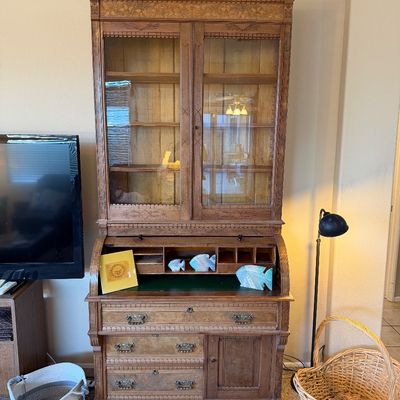 Antique carved oak cylinder roll-top secretary desk with a glass-front upper hutch cabinet, featuring intricate floral accents and...