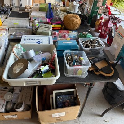 Assorted household goods, garage items, and hardware, including tape, plastic organizers, picture frames, and holiday decorations,...