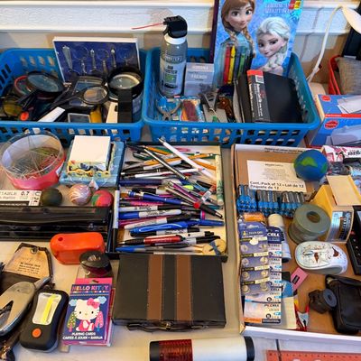 Large assortment of office supplies and small household items including pens, batteries, magnifiers, a Frozen coloring book, and small...