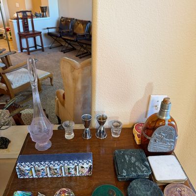 Collection of barware and decor including a vintage liquor decanter with pewter emblem, pink glass ewer, metal jiggers, marble and...