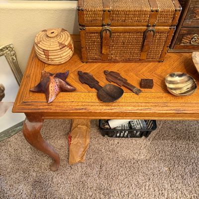 Collection of decorative tabletop accents including a woven wicker storage trunk with leather trim, a small coiled basket, carved wooden...