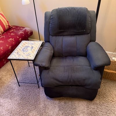 Plush dark blue fabric recliner paired with a black metal accent table featuring a decorative tiled top.