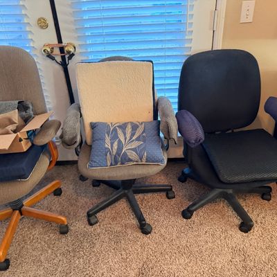 Trio of upholstered rolling office task chairs with added cushions and covers.