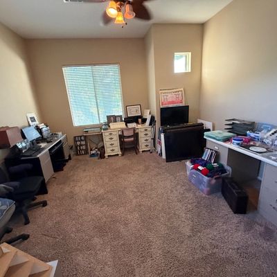 Home office and craft room featuring multiple computer desks, office chairs, a vintage white kneehole desk, craft supplies, and electronics.