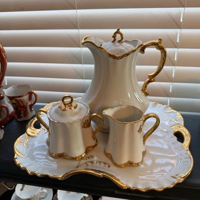 Vintage white porcelain coffee and tea service set with heavy gold trim, including a tall pot, creamer, lidded sugar bowl, and matching...