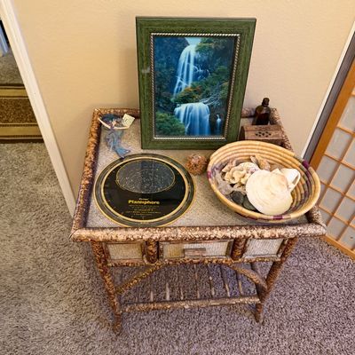 Faux tortoiseshell bamboo and wicker accent table displayed with decor items including framed waterfall art, a Philips' Planisphere,...