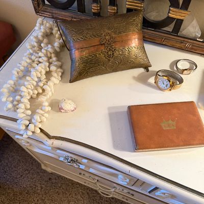Vintage accessories including an embossed brass metal clutch, long shell necklaces, two wristwatches, and a leather case with a gold...