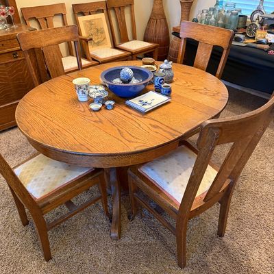 Antique Arts and Crafts style oak pedestal dining table with a set of matching chairs featuring upholstered seats.
