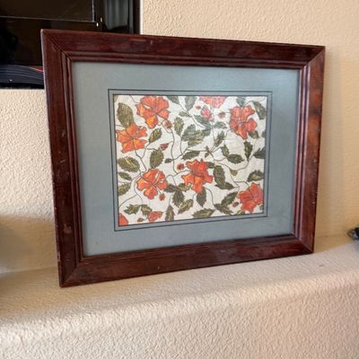 Framed botanical drawing featuring orange flowers and green foliage, housed in a reddish-brown wooden frame with double matting.