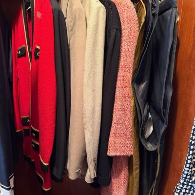 Selection of women's vintage tailored jackets, coats, and suit sets hanging in a wooden closet.