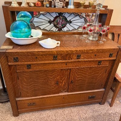 Antique Arts and Crafts style tiger oak sideboard with mirror back and top shelf, displayed with assorted glassware and decorative...