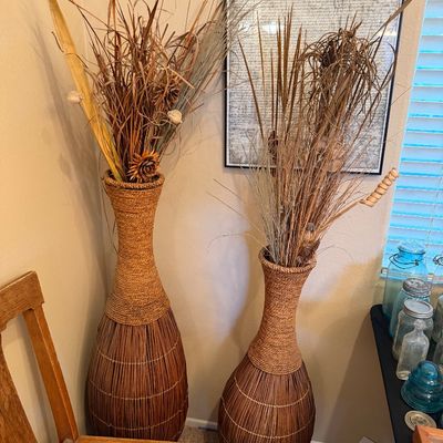 Pair of tall woven floor vases with rope-wrapped necks, filled with decorative dried floral arrangements.