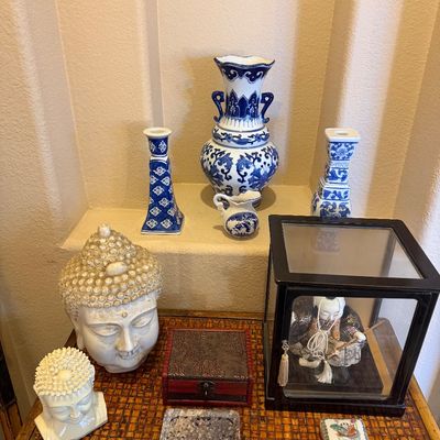 Collection of Asian-inspired decor items, including blue and white porcelain vases, ceramic Buddha head sculptures, and a framed display...