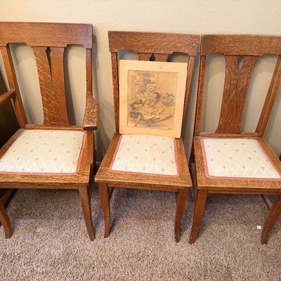 Set of three antique quarter-sawn oak dining chairs, including one armchair, featuring patterned upholstered seat cushions.