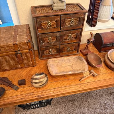 Collection of rustic wooden decor items including a wicker-paneled six-drawer mini chest, a stone Ganesha statue, a wicker trunk, and...