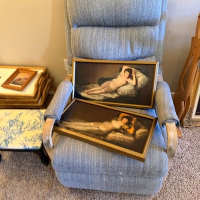 Pair of framed prints depicting Francisco Goya's The Nude Maja and The Clothed Maja, resting on a light blue upholstered recliner.