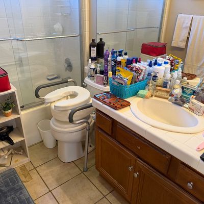 Bathroom full of varied personal care items, cosmetics, toiletries, hair styling tools, and medical safety equipment including a toilet...