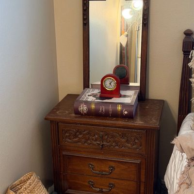 Traditional dark wood nightstand featuring carved drawer detailing, accompanied by a matching wall-mounted or attachable vanity mirror.