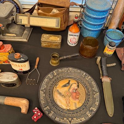 Collection of vintage collectibles including a decorative Aztec-style wall plaque, military-style sheath knife, blue speckled enamel...