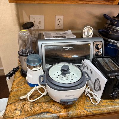 A collection of small kitchen counter appliances, including a Hamilton Beach toaster oven, a Black+Decker rice cooker, a two-slice...