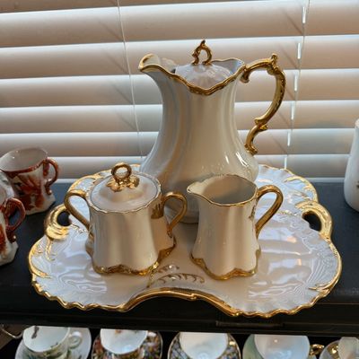 Vintage white porcelain coffee service set featuring heavy gold trim accents, including a coffee pot, sugar bowl, creamer, and matching...