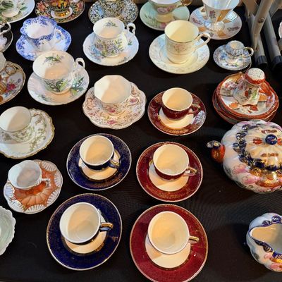 Large collection of vintage fine china teacups and saucers, featuring floral patterns, gilt trims, and matching tea service pieces.