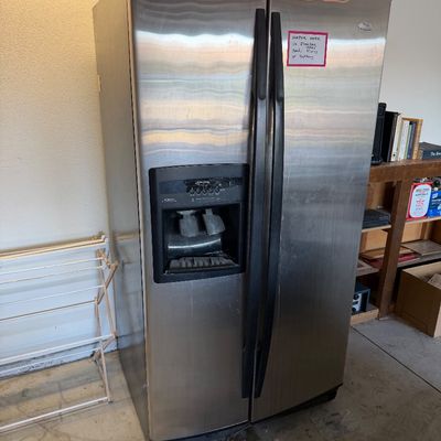 Whirlpool stainless steel side-by-side refrigerator featuring an exterior water and ice dispenser with black handles.