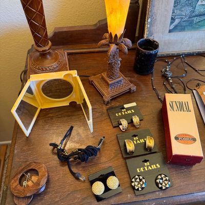 Collection of vintage costume jewelry, including M Details earrings on cards, alongside a palm tree accent lamp and a yellow tri-fold...