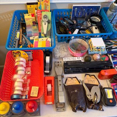 Assorted vintage and modern office supplies, including tape dispensers, staplers, handheld hole punches, magnifiers, and stationery...