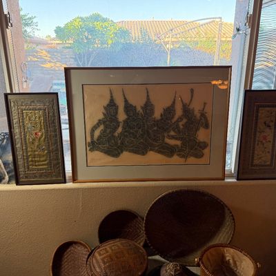 Framed Asian artwork including a Thai charcoal rubbing of musicians, a pair of embroidered silk panels, and a print, displayed above...