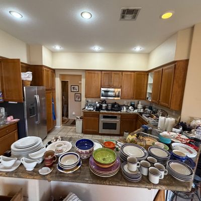 Kitchen island and countertops filled with an extensive collection of ceramic dishware, mugs, bowls, and serving pieces for sale.