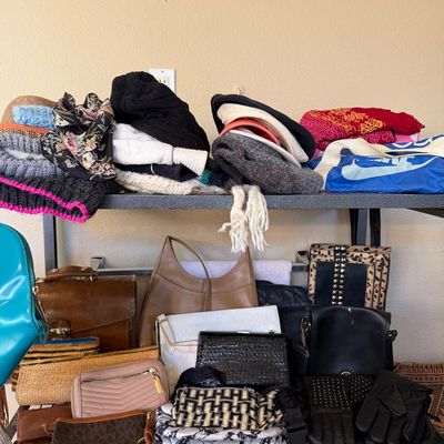 Collection of women's fashion accessories including knit beanies, scarves, leather handbags, clutches, and gloves arranged on a...