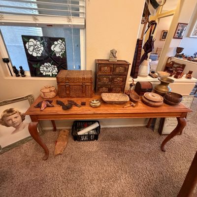 Wooden sofa table displayed with various decorative items including a small woven chest, miniature drawer unit, brass vessels, and carved...