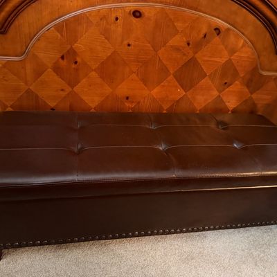 Sale Photo Thumbnail #114: Contemporary dark brown faux leather storage ottoman bench with tufted top and nailhead trim, placed in front of a wooden headboard.