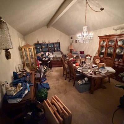 Formal dining room filled with traditional furnishings, including a large wooden hutch, a matching dining table set with crystal, and a...
