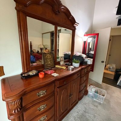 Traditional carved wood dresser with attached tri-fold arched mirror and ornate brass hardware.