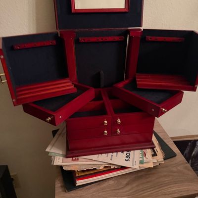 Vintage cherry red wooden jewelry armoire featuring multi-tiered fold-out compartments, brass knobs, necklace hooks, and a built-in...