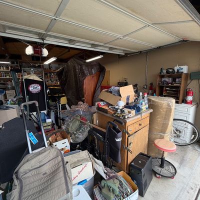 Assorted household goods, tools, luggage, and garage items including a rolling computer tower, stool, and wooden cabinet.