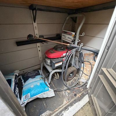 Powerstroke 2600 PSI gas-powered pressure washer with Honda GCV160 engine, stored alongside bags of Morton water softener salt in a...