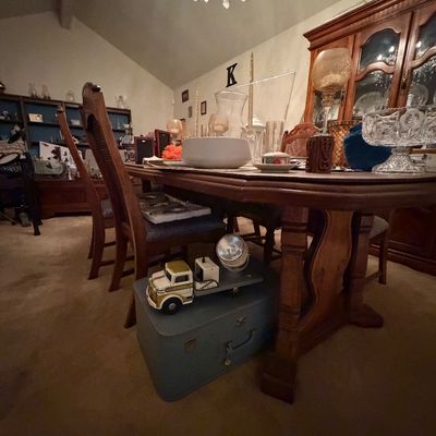 Dining room table set with glassware and decor, featuring a vintage toy truck on a suitcase stored underneath.