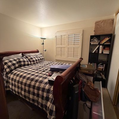 Traditional cherry-finished sleigh bed frame with black-and-white buffalo plaid bedding, alongside a dark wood tall bookcase and room...