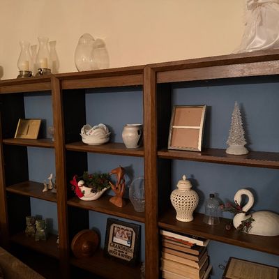 Large wooden multi-section bookcase unit with blue painted backboards, filled with various decorative knick-knacks, glassware, picture...