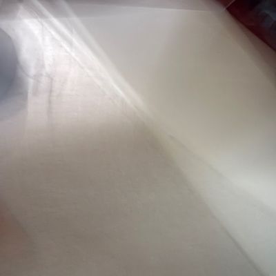Extremely blurry and out-of-focus photo of a light-colored surface, possibly a mattress or fabric.