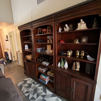 Large dark wood multi-unit wall entertainment cabinet with open shelving and lower cabinet storage, displayed with assorted home decor...
