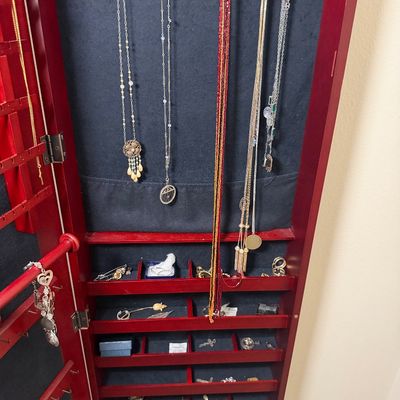 Sale Photo Thumbnail #104: Standing cherry wood jewelry armoire with black felt lining, filled with various necklaces, brooches, and costume jewelry pieces.