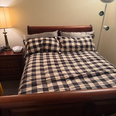 Wooden sleigh bed frame with a dark cherry finish, dressed in a black and white buffalo plaid comforter set.
