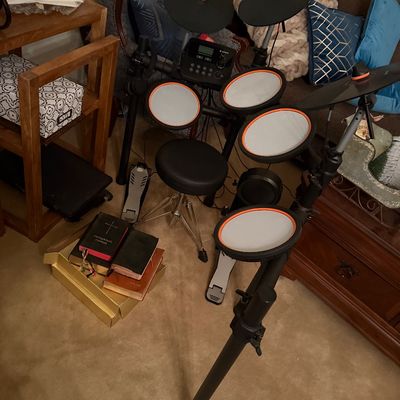 Alesia electronic drum kit setup with mesh pads, cymbals, sound module, foot pedals, and an adjustable drum throne.