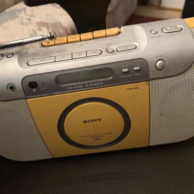 Vintage Sony CFD-E100 yellow and silver portable CD radio cassette-corder boombox with a telescopic antenna.