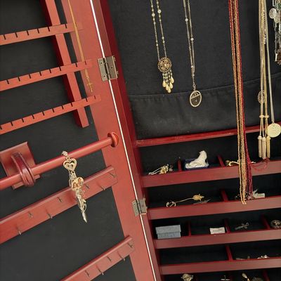 Open cherry-finish wooden standing jewelry armoire, lined in black velvet and filled with an assortment of vintage costume jewelry,...
