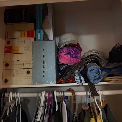 Closet shelf containing a vintage Kodak Carousel projector in its box, multiple boxed carousel slide trays, and an assortment of baseball...